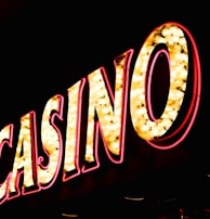 Brightly illuminated letters spell out 'CASINO' with glowing yellow bulbs and red outlines against a dark background.