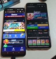 Two smartphones are displayed on a white surface, both showing gambling websites with colorful graphics, text, and various options for logging in and accessing games. The screens are bright and filled with promotional content related to casino and slot games.